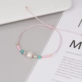 Dettaglio del bracciale rosa intrecciato con perla d'acqua dolce e turchese - Rosa