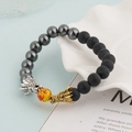 Detailed close-up of beaded dragon bracelet with lava stone and tiger eye on a shell tray - Black And Hematite