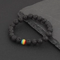 Black lava rock beaded bracelet with a rainbow accent bead on a dark stone background - Rainbow Lava Stone (BNS-0294)