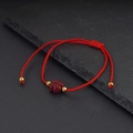 Bracciale rosso intrecciato con quadrifoglio in cinnabro e perle dorate su sfondo di pietra - Rosso
