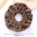Macro detail van een 13cm bruine fluwelen scrunchie met klassieke zwarte stippen - koffiekleur