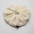 Detailopname van een oversized crème pluche scrunchie met zachte imitatiebont textuur en label - Beige