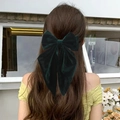 Deep green velvet 8-inch hair bow clip for women shown on a model in an outdoor setting - Streamer Bow Style