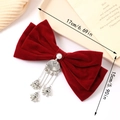 Close-up of a large red velvet bow hair clip with silver bells and tassel charms - Burgundy