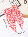 Detail of oversized white bow hair clip with red lip print and long flowing streamers - D (Lip Print)
