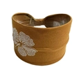 Detailansicht eines braunen elastischen Stirnbands mit glänzendem Strass-Blumenmuster - Braun