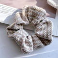 Braunes und weißes Strick-Haargummi mit Hahnentrittmuster auf Magazinhintergrund - Beige