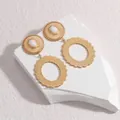 Elegant gold-tone geometric oval hollow earrings with white bead inlay on marble background - White