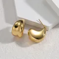 Detailed macro shot of elegant gold-toned C-shaped titanium steel earrings on a white stone - Gold