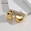 Detailaufnahme eleganter goldfarbener C-förmiger Titanstahl-Ohrringe auf weißem Stein - Gold