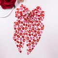 Detail of oversized bow hair clip featuring red lip prints and long elegant ribbons - White Lip Print