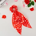 Détail d'un chouchou en satin rouge avec motifs de cœurs blancs et longs rubans - Base Rouge LOVE