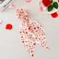 Détail du chouchou en satin crème avec cœurs rouges et imprimé LOVE et pétales - Base Blanche LOVE
