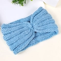 Detail of light blue chunky knit baby headband with a stylish cross-knot texture - Blue