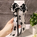 Dettaglio di un fiocco in raso nero con nastri in chiffon floreale e perle - Stile Nastro Floreale