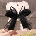 Detail of a vintage black lace bow hair clip with a pearl pendant on bear-shaped carding - Black