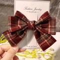 Dettaglio del fermaglio a fiocco scozzese rosso e marrone con glitter dorati su carta - Rosso
