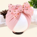 Detail van de gebreide textuur van de roze babytulband met gouden polkadot strik - Sneeuwknop met Stippen