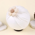 Detailed close-up of white baby turban featuring hollow embroidery and a 3D fabric flower - White with Apricot Flower