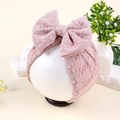 Détail d'un turban en tricot rose pour bébé avec un grand nœud sur tête de mannequin - Rose