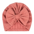 Détail du bonnet à nœud pour bébé montrant la texture gaufrée en rose poudré délicat - Vieux Rose