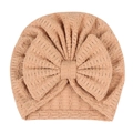 Gros plan d'un bonnet turban beige pour nouveau-né avec un nœud gaufré et tissu plissé - Café Clair