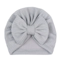 Gros plan détaillé du bonnet pour bébé en tricot gris clair avec grand nœud et texture - Gris