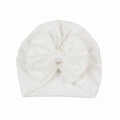Detail van witte gebreide babymuts met verfijnd kantpatroon en een grote decoratieve strik - Wit