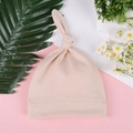 Detail view of pink newborn knotted beanie hat on a decorative floral background - One Size / Light Coffee