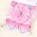 Dettaglio del set fascia neonata con fiore rosa e occhiali da sole a cuore su carta - Stile Fiore Grande / Rosa