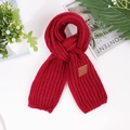 Detail shot of burgundy chunky knit scarf featuring a brown leather label and vertical ribs - Burgundy