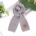 Flat lay of gray chunky knit children's scarf with a brown leather logo patch - Gray