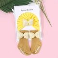 Detail von gelbem Baby-Strickhauben- und Sockenset mit glänzenden Pailletten-Schleifen - Mütze Und Socken Set / Gelb