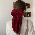 Detail view of a large burgundy velvet bow hair clip with long ribbons on hair - Burgundy