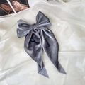 Macro shot of grey velvet bow hair clip with long ribbons on soft white fabric - Gray