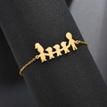 Vista macro del bracciale con ciondolo famiglia in oro su supporto cilindrico nero - Oro