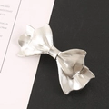 Elegante zilveren metalen haarclip in strikvorm met geplooide textuur op zwart-wit decor - Zilver