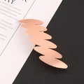 Nahaufnahme der roségoldenen gewellten Haarspange aus Metall mit matter Texturierung - Roségold