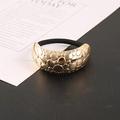 Dettaglio di un elastico dorato con texture a pois su sfondo bianco e nero elegante - Oro