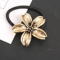 Detailansicht des hochelastischen schwarzen Haargummis mit matter goldener Legierungsblume - Bronze