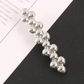 Detail view of silver beaded hair clip with metallic spheres on a magazine background - Silver