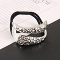 Macro-opname van zilveren haarelastiek met lavastructuur en onregelmatige metallic finish - Zilver