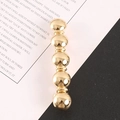 Minimalist gold metal hair clip with glossy spherical design on black and white background - Gold
