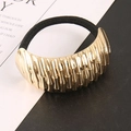 Detail eines goldenen Metallschmucks mit Bambustextur an einem schwarzen Haargummi - Gold