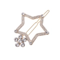 Golden hollow star hair clip with crystals and pearl flower detail on white background - Gold Tone Rhinestone Style