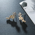 Detail of gold climber earrings with star shapes and sparkling rhinestones on grey background - Gold