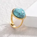 Vista macro de un anillo vintage dorado con piedra turquesa ovalada y textura mineral - Azul