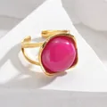 Detalle de anillo dorado vintage con gema rosa sobre piedra geométrica blanca - Rosa Rojo