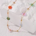 Macro di ciondoli a fiore colorati su una collana minimalista in acciaio inossidabile oro - Collana a fiorellini
