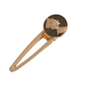 Macro detail of a vintage gold alloy hair clip featuring a classic goddess relief emblem - Coffee